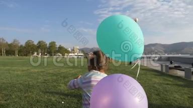 可爱的小女孩<strong>拿</strong>着<strong>气球</strong>在公园里跑，笑着